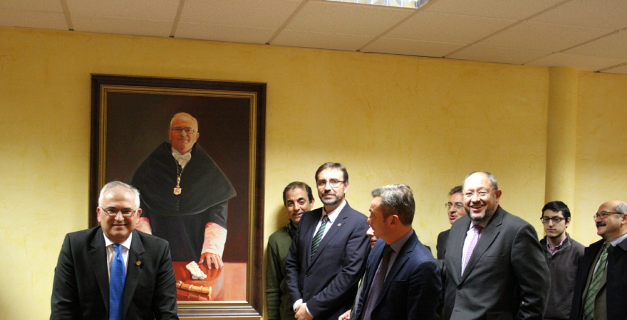 Manuel Parras posa junto a su retrato, ante la mirada del Rector Juan Gómez y responsables de universidades andaluzas