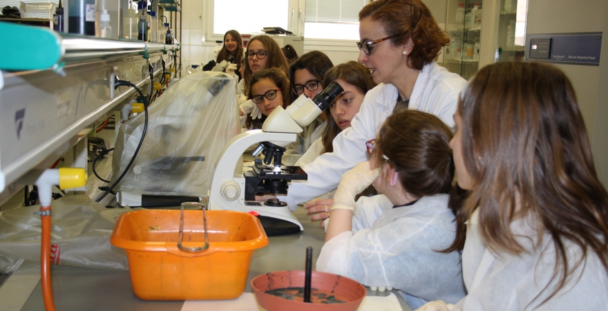 Hikmate Abriouel explica el funcionamiento del microscopio a varias alumnas que han participado en el taller. 