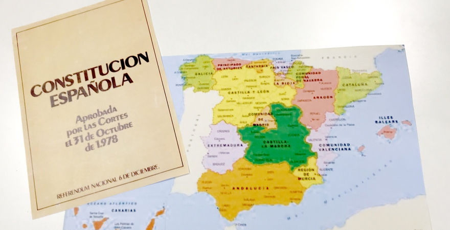 Portada de la Constitución Española, junto a un mapa político de España.