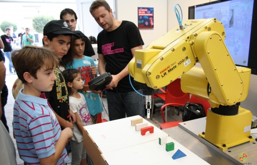 Javier Gámez muestra el funcionamiento de un autómata a unos niños.
